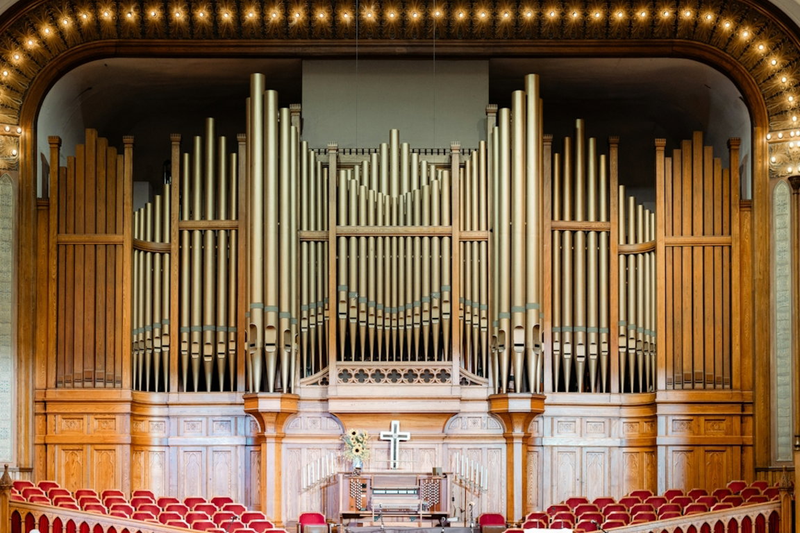 a large pipe organ in a church with red seats